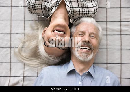 Joyeux couple marié d'âge mûr couché sur des draps à carreaux Banque D'Images