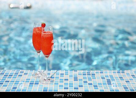 Verres de champagne à la fraise sur fond bleu turquoise. Cocktail Rossini. Summer pool party Banque D'Images