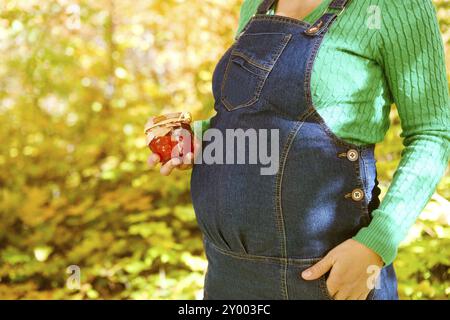 Happy pregnant woman dans la forêt d'automne. Close up on belly Banque D'Images