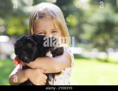 Cute little girl hugging dog puppy à l'extérieur. L'amitié et de concept de soins Banque D'Images