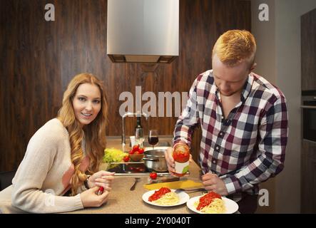 Couple heureux dans une cuisine la cuisson des pâtes et de boire le vin rouge Banque D'Images