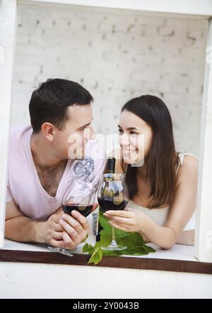 Jeune couple heureux dégustant un verre de vin rouge sur la terrasse Banque D'Images