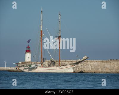 Grand voilier dans le port à côté d'un phare, surface de mer calme sous un ciel bleu clair, ibiza, mer méditerranée, espagne Banque D'Images