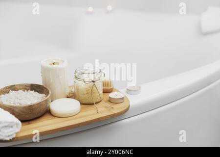 Préparation pour le soin spa de l'hôtel, la procédure de bain à la maison. Lavabo blanc dans la salle de bains, accessoires sur le plateau bougies allumées, savon, brosse à pied, serviette, Banque D'Images