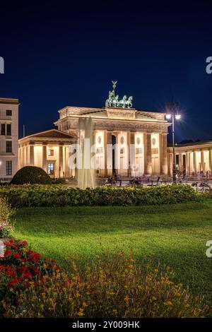 La porte de Brandebourg illuminée à Berlin avec une fontaine d'eau la nuit Banque D'Images