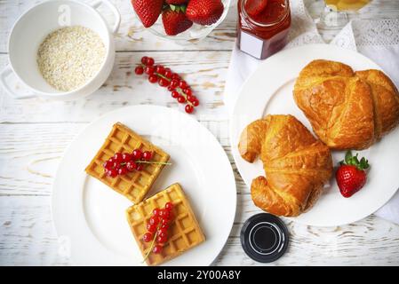 Gaufres aux fruits et de la confiture de groseille rouge sur une assiette blanche, croissants, jus d'orange et de flocons d'avoine Gruau sur le fond en bois Banque D'Images