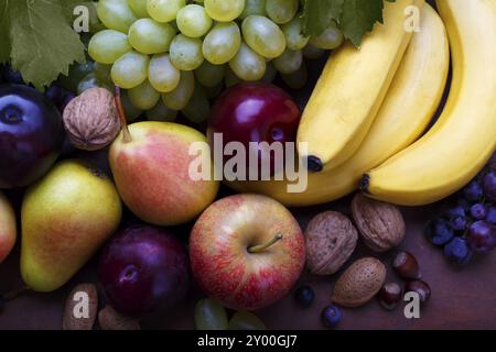 Fruits mûrs sur fond rustique avec Copyspace. Banane, poire, prune, pêche, pommes, raisins rouges et blancs Banque D'Images