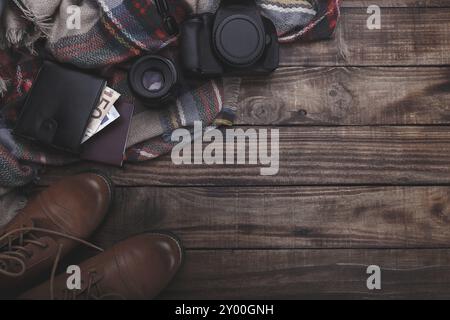 Les accessoires du photographe camera lense thermos avec de l'argent sac à main bottes et plaid ancienne grange sur le bloc-notes de fond bois Banque D'Images