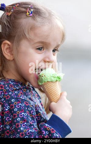 Mignonne petite fille blonde mangeant de la crème glacée et s'amusant Banque D'Images