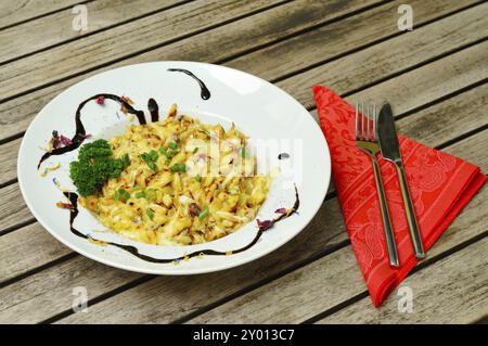 Spaetzle au fromage sur une assiette avec une salade. Nouilles au fromage avec salade sur une table en bois Banque D'Images