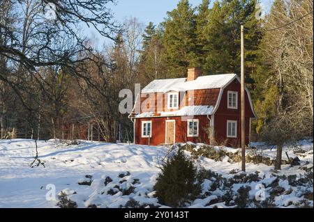 Maison en bois peinte en rouge dans un paysage hivernal en Suède Banque D'Images