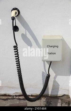 Point de recharge pour voiture électrique sur le mur blanc de la chambre Banque D'Images