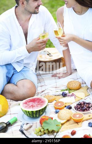 Jeune couple amoureux sur pique-nique estival toasting with white wine Banque D'Images