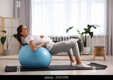 Belle femme enceinte faisant des exercices sur fitball à la maison Banque D'Images