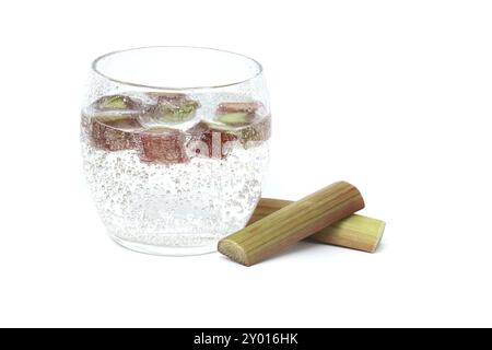 Verre transparent rempli d'eau froide et de plusieurs morceaux de rhubarbe isolé sur fond blanc Banque D'Images