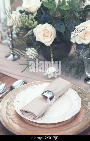 Bougies et vase avec des roses blanches placées sur la table ronde près des verres à vin pendant la date romantique dans le jardin Banque D'Images