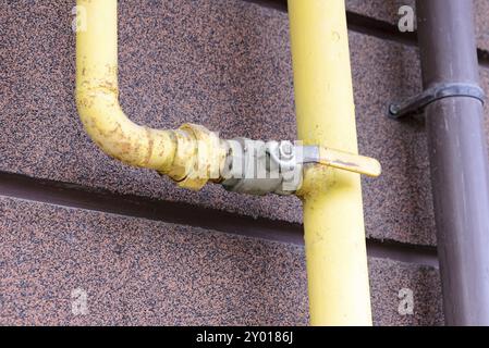 Un tube à gaz jaune, avec robinet, à l'extérieur d'une maison pour canaliser l'énergie douce à la maison Banque D'Images