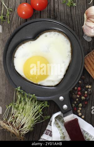 Œuf frit en forme en forme de cœur avec le cresson, tomate, ail et poivre Banque D'Images