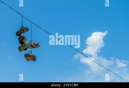 Vieilles chaussures accroché sur le fil à haute tension on blue sky backgroun Banque D'Images