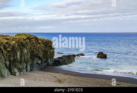 Voir des roches à Black Beach et l'océan Atlantique Nord dans le nord de l'Islande Banque D'Images