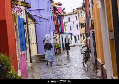 Vue sur la ville de Burano avec des maisons colorées et des canaux. Temps pluvieux, les gens portent des parapluies. Burano, Venise, Venise, Italie, Europe Banque D'Images