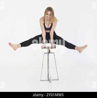 Jeune femme fit de la formation. Beau travail de l'athlète féminine dehors pour le bien-être de la salle de sport, la formation des muscles des jambes. Elle soulève ses jambes à l'aide d'une chaise Banque D'Images