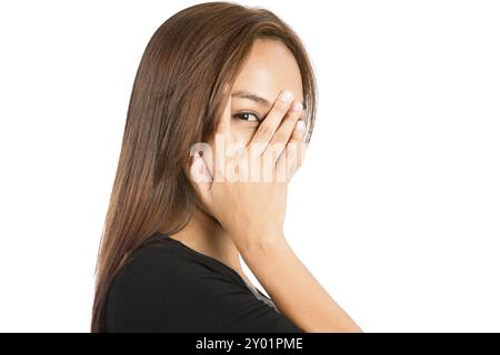 Gros plan portrait d'une femme asiatique joueuse regardant la caméra jetant un coup d'œil à travers les doigts fendus, la main couvrant le visage montrant la peur, l'intérêt, la curiosité timide, Banque D'Images