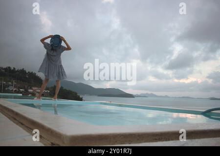 Dolsan-eup, Yeosu-si, Corée du Sud - 26 juillet 2024 : jeune femme regardant le lever du soleil dans un complexe avec piscine donnant sur la mer à Yeosu Banque D'Images