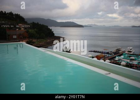 Dolsan-eup, Yeosu-si, Corée du Sud - 26 juillet 2024 : jeune femme regardant le lever du soleil dans un complexe avec piscine donnant sur la mer à Yeosu Banque D'Images