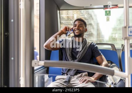 Homme d'affaires occasionnel africain sur le chemin du travail assis dans le bus parlant au mobile Banque D'Images