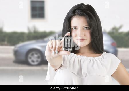 Femme tenant des clés de voiture avec une voiture à l'arrière-plan Banque D'Images