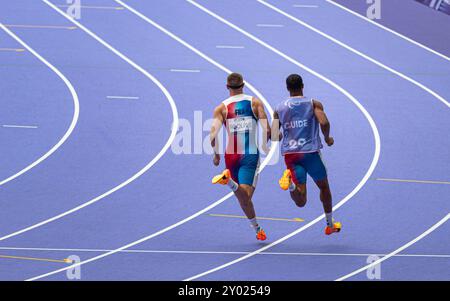 L’athlète paralympique français aveugle Timothée Adolphe avec son guide courant pour le 400m au stade de France pour les Jeux Paralympiques de Paris 2024. Banque D'Images