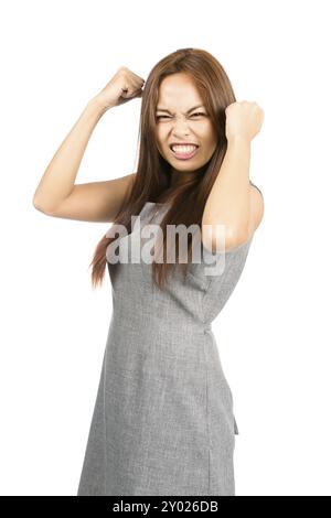 Profil d'une fille asiatique déçue avec les cheveux brun clair, les dents serrées, les poings boules, froncement des sourcils pendant le tantrum tempéré, fatiguée, agacée et irritée. Banque D'Images