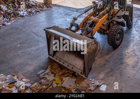 Pelle orange travaillant les déchets recyclés dans une usine de recyclage à Switrzerland. Recyclage du papier. Banque D'Images