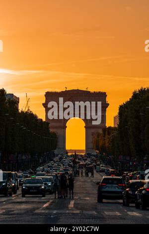 Paris, France - 10 août 2024 : circulation animée et foule au carrefour des champs-Élysées avec Arc de Triomphe au coucher du soleil Banque D'Images