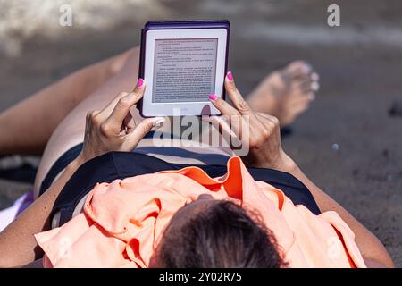 femme lisant un ebook couché sur la plage Banque D'Images