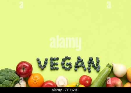 Mot VEGAN fait de myrtilles avec différents fruits et légumes sur fond vert Banque D'Images
