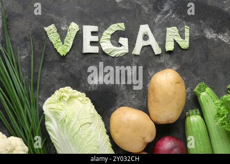 Mot VEGAN fait de chou et de différents légumes frais sur fond noir Banque D'Images
