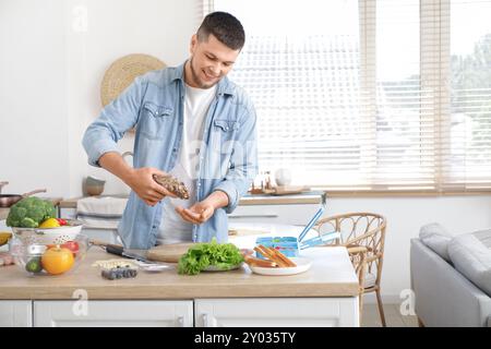 Jeune homme avec des noix emballant la boîte à lunch dans la cuisine Banque D'Images