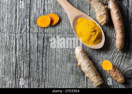 Poudre de curcuma dans une cuillère ou un bol et racine de curcuma frais sur fond de bois, concept d'épices, ( curcuma longa ) Banque D'Images