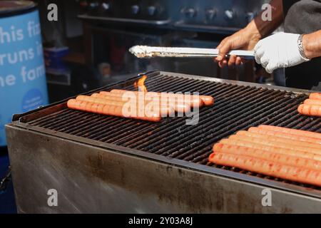 Une vue des wieners de hot-dog et des saucisses grillant sur un grand barbecue, vu à un carnaval local. Banque D'Images