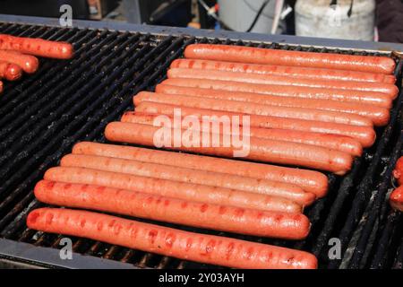 Une vue des wieners de hot-dog et des saucisses grillant sur un grand barbecue, vu à un carnaval local. Banque D'Images