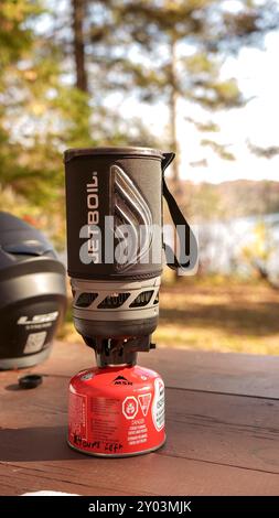 Motocycliste fait de l'eau bouillante dans la forêt boisée d'automne tout en campant dans une ébullition instantanée Jetboil et un petit réservoir de gaz. Ottawa ON Canada - 07,27 Banque D'Images