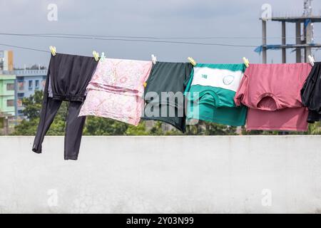 Les vêtements mouillés sont suspendus à une corde à linge avec des pinces à linge sur un toit, séchant au soleil et au vent. Banque D'Images