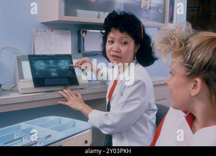 Orthodontiste vietnamo-américain examinant les radiographies d'un adolescent en clinique dentaire. ©Bob Daemmrich Banque D'Images