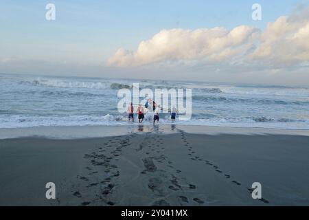 Purworejo, Java central, Indonésie. 30 août 2024. De petits bateaux transportant deux à trois pêcheurs ont bravé de hautes vagues par mauvais temps pour aller pêcher à la plage de Jatimalang sur AÄŸust, 30, 2024. Le mauvais temps et les vents violents n’ont pas découragé les pêcheurs de partir en mer. Ils ont utilisé leur instinct et leurs connaissances pour braver les vagues de huit mètres de haut pour se rendre au milieu de la mer, seuls quelques bateaux de pêche ont osé commencer à pêcher dès l’aube et revenir à midi parce qu’ils ne voulaient pas prendre trop de risques pendant la mauvaise saison météo. (Crédit image : © Dasril Roszandi/ZUMA Press Wire) EDITORIAL Banque D'Images