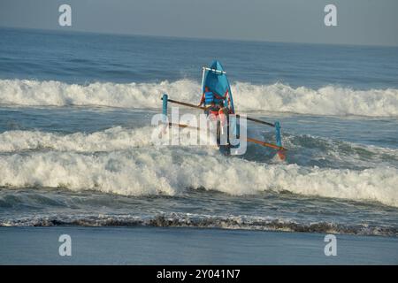 Purworejo, Java central, Indonésie. 30 août 2024. De petits bateaux transportant deux à trois pêcheurs ont bravé de hautes vagues par mauvais temps pour aller pêcher à la plage de Jatimalang sur AÄŸust, 30, 2024. Le mauvais temps et les vents violents n’ont pas découragé les pêcheurs de partir en mer. Ils ont utilisé leur instinct et leurs connaissances pour braver les vagues de huit mètres de haut pour se rendre au milieu de la mer, seuls quelques bateaux de pêche ont osé commencer à pêcher dès l’aube et revenir à midi parce qu’ils ne voulaient pas prendre trop de risques pendant la mauvaise saison météo. (Crédit image : © Dasril Roszandi/ZUMA Press Wire) EDITORIAL Banque D'Images