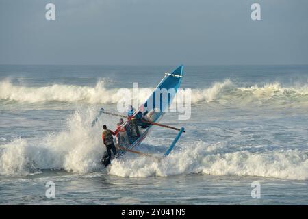 Purworejo, Java central, Indonésie. 30 août 2024. De petits bateaux transportant deux à trois pêcheurs ont bravé de hautes vagues par mauvais temps pour aller pêcher à la plage de Jatimalang sur AÄŸust, 30, 2024. Le mauvais temps et les vents violents n’ont pas découragé les pêcheurs de partir en mer. Ils ont utilisé leur instinct et leurs connaissances pour braver les vagues de huit mètres de haut pour se rendre au milieu de la mer, seuls quelques bateaux de pêche ont osé commencer à pêcher dès l’aube et revenir à midi parce qu’ils ne voulaient pas prendre trop de risques pendant la mauvaise saison météo. (Crédit image : © Dasril Roszandi/ZUMA Press Wire) EDITORIAL Banque D'Images