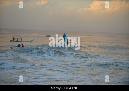 Purworejo, Java central, Indonésie. 30 août 2024. De petits bateaux transportant deux à trois pêcheurs ont bravé de hautes vagues par mauvais temps pour aller pêcher à la plage de Jatimalang sur AÄŸust, 30, 2024. Le mauvais temps et les vents violents n’ont pas découragé les pêcheurs de partir en mer. Ils ont utilisé leur instinct et leurs connaissances pour braver les vagues de huit mètres de haut pour se rendre au milieu de la mer, seuls quelques bateaux de pêche ont osé commencer à pêcher dès l’aube et revenir à midi parce qu’ils ne voulaient pas prendre trop de risques pendant la mauvaise saison météo. (Crédit image : © Dasril Roszandi/ZUMA Press Wire) EDITORIAL Banque D'Images