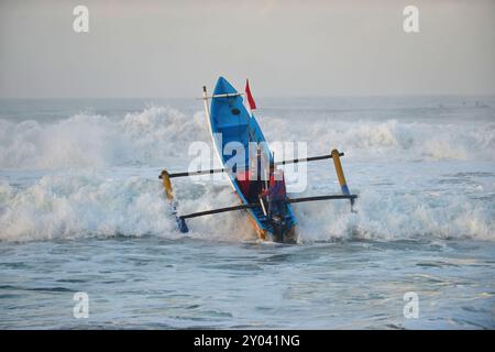 Purworejo, Java central, Indonésie. 30 août 2024. De petits bateaux transportant deux à trois pêcheurs ont bravé de hautes vagues par mauvais temps pour aller pêcher à la plage de Jatimalang sur AÄŸust, 30, 2024. Le mauvais temps et les vents violents n’ont pas découragé les pêcheurs de partir en mer. Ils ont utilisé leur instinct et leurs connaissances pour braver les vagues de huit mètres de haut pour se rendre au milieu de la mer, seuls quelques bateaux de pêche ont osé commencer à pêcher dès l’aube et revenir à midi parce qu’ils ne voulaient pas prendre trop de risques pendant la mauvaise saison météo. (Crédit image : © Dasril Roszandi/ZUMA Press Wire) EDITORIAL Banque D'Images